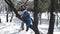 A little boy in a snowy winter park climbs a tree and waves a pen into the camera
