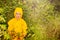 Little boy stand hide from rain under the bush