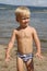 Little boy standing on the beach near the river