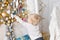 A little boy stands near a lot of gifts. Happy new year. decorated Christmas tree. Christmas morning in bright living