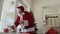 Little boy steal Santa`s bag of presents while Santa taste cookies and milk