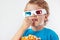 Little boy in stereo glasses eating popcorn