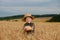 Little boy in the straw hat and shirt he held out his handing with bread in ripe grain. concept poverty, crisis, famine