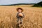 Little boy in the straw hat and shirt he held out his handing with bread in ripe grain. concept poverty, crisis, famine