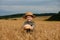 Little boy in the straw hat and shirt he held out his handing with bread in ripe grain. concept poverty, crisis, famine