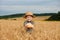 Little boy in the straw hat and shirt he held out his handing with bread in ripe grain. concept poverty, crisis, famine