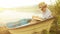 Little boy in a straw hat sitting in the rustic boat reading a book