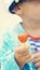 Little boy in a striped t-shirt and captain`s cap sitting on the beach with candy in mouth