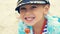 Little boy in a striped t-shirt and captain`s cap sitting on the beach with candy in mouth