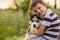 A little boy in a striped t-shirt lovingly hugs his pet husky dog outdoors