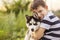 A little boy in a striped t-shirt lovingly hugs his pet husky dog outdoors