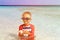 Little boy swimming holding shell on beach