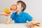 Little boy at the table chooses between fastfood and healthy diet on white background