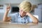 Little boy with tablet raising hand at school