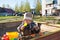 A little boy of three years old is playing on a cool spring sunny day in the sandbox in the city yard with his toy truck