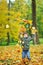 Little boy tossing leaves in autumn park