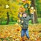 Little boy tossing leaves in autumn park