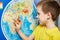 Little boy with toy giraffe shows Africa on world map
