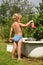 Little boy with toy watering can, poured water. summer day