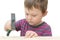 Little boy tries to hammer in a nail with a hammer. The idea is the development of fine motor skills, teaching children in a