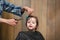A little boy is trimmed in the hairdresser`s bright emotions on