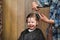 A little boy is trimmed in the hairdresser`s bright emotions on