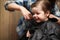 A little boy is trimmed in the hairdresser`s bright emotions on