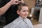A little boy is trimmed in the hairdresser`s bright emotions