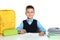 Little boy in uniform doing assignment at desk against white background