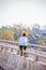Little boy - unrecognizable- climbing on bridge over river pausing to look out over wooded residential area - blurred bokeh
