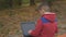 Little boy uses laptop in autumn park