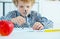 Little boy using engineer divider compass to measure the distance on paper.