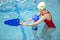 Little boy using the kickboard for learning to swim with trainer in the swimming pool