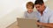 Little boy using laptop with his father at the table