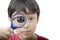 Little boy using magnifier close up on white background