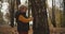 Little boy is viewing and touching bark on trunk of tree in forest at autumn, child is exploring environment