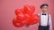 Little boy in vintage clothes with heart-shaped balloons smiling, Valentines day