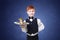 Little boy waiter stands with gray kitten on tray