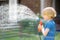 Little boy watering lawn and playing with garden hose with sprinkler in sunny backyard. Preschooler child having fun with spray of