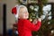 Little boy wearing Santa hat ready for celebrate Christmas. Cute child decorating the Christmas tree with glass toy