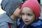 Little boy whispers a secret to girl wearing winter hats