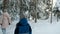 Little boy and woman walk in winter coniferous forest. View from back.