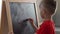 Little boy writes math equations on the chalkboard and solves them