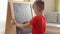 Little boy writes math equations on the chalkboard and solves them