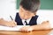 Little boy writing homework in classroom