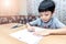 Little boy writing homework on wooden table at home. Kid learing and writing alphabet looking very happy