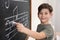 Little boy writing music notes on blackboard