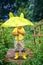 A little boy in yellow boots hides under a yellow umbrella. rain