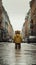 A little boy in a yellow jacket walks along the street.