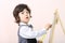 Little boy with yellow pointer draws with chalk on chalkboard